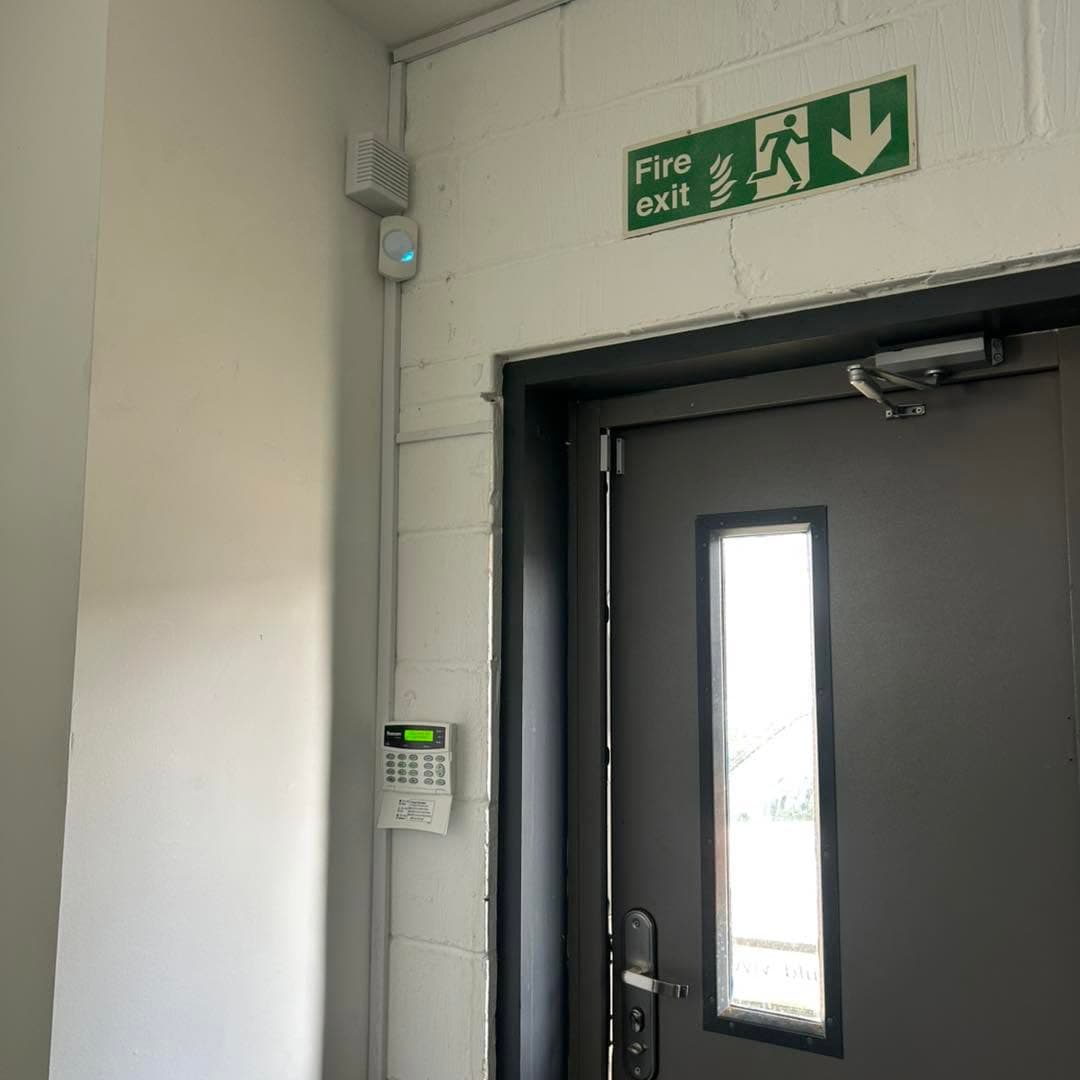 Commercial entrance with an intruder alarm keypad and detector installed nearby