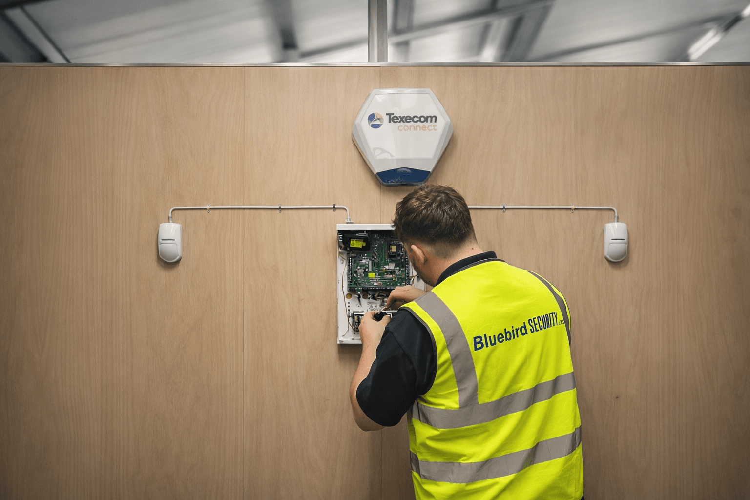 Bluebird engineer working on an alarm panel during installation or training